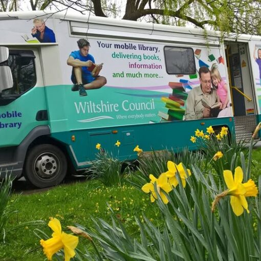 An image of Wiltshire Mobile Library with green grass and daffodils